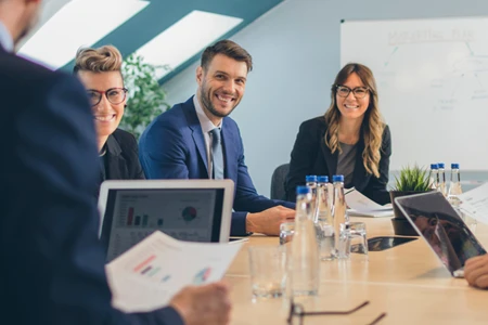 Two women and men sitting at the meeting smiling and working together